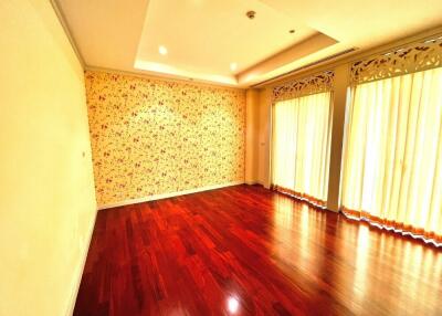 Spacious bedroom with hardwood floors, floral wallpaper, large windows, and ample lighting