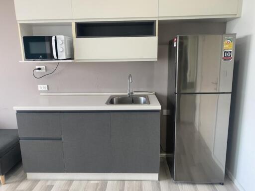 Modern kitchen with gray cabinets, stainless steel fridge, microwave, sink, and white countertops