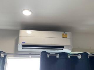 Air conditioner unit installed above a window with curtains