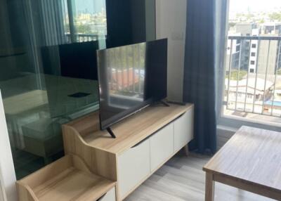 Living room with large window, TV on stand, and wooden furniture