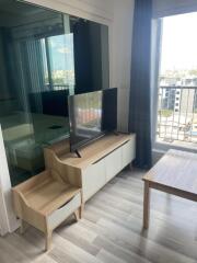 Living room with large window, TV on stand, and wooden furniture