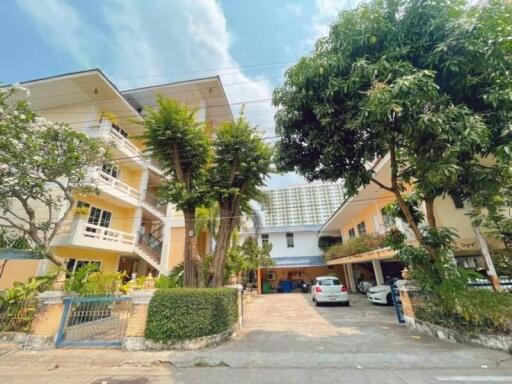 Front exterior view of residential building with parking area and greenery