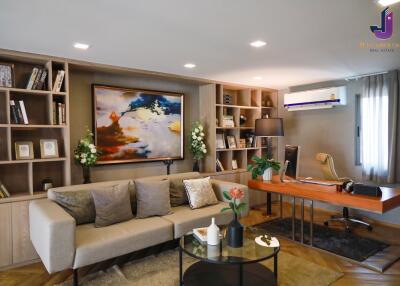 Modern living room with sofa, bookshelf, wall art, and a workspace