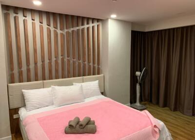 Master bedroom with modern wooden wall design, double bed and floor fan