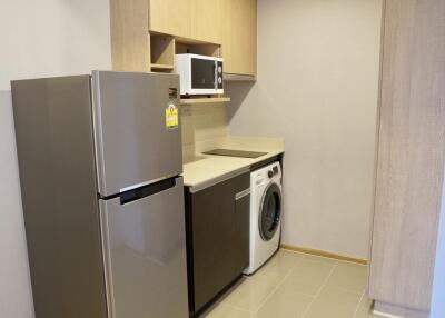Modern kitchen with fridge, microwave, washing machine and ample cabinetry