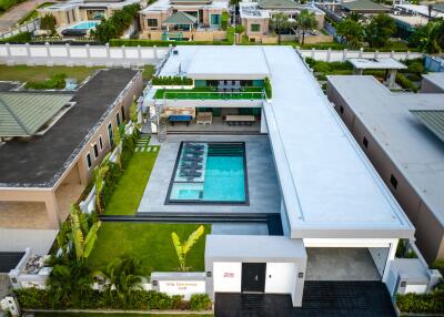 Aerial view of a modern villa with a central swimming pool and surrounding greenery