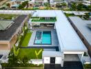 Aerial view of a modern villa with a central swimming pool and surrounding greenery