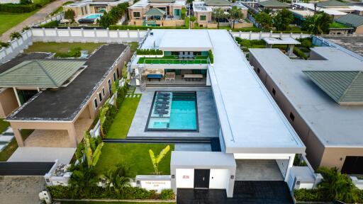 Aerial view of a modern villa with a central swimming pool and surrounding greenery