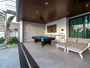 Modern outdoor living area with a pool table, seating, and spiral staircase