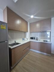 Modern kitchen with wooden cabinets, stainless steel appliances, and white countertops.