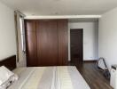 Bedroom with wooden wardrobe, bed, and window