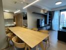 Modern living and dining area with large wooden table, TV, and large window