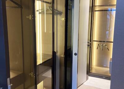 Modern walk-in closet with glass doors and ample lighting