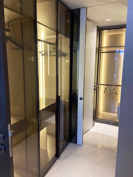 Modern walk-in closet with glass doors and ample lighting