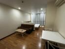 Modern studio apartment with a wooden floor, small sofa, coffee table, bed, and dining table with chairs