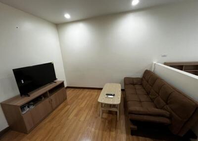 Living room with television, sofa, and wooden floor