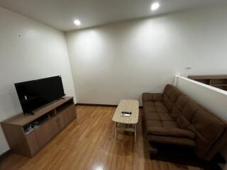 Living room with television, sofa, and wooden floor