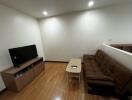 Living room with television, sofa, and wooden floor