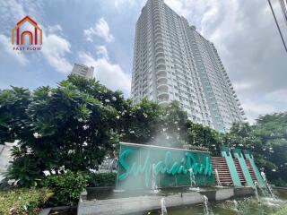 High-rise residential building with water feature and green landscaping