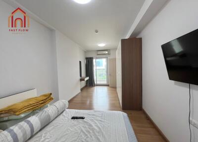 Modern bedroom with TV, balcony access, and wooden flooring