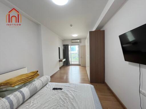 Modern bedroom with TV, balcony access, and wooden flooring