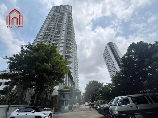 Tall residential building with parking space and trees