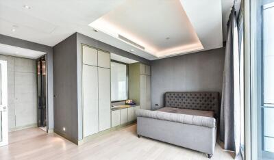 Modern bedroom with gray upholstered bed, built-in wardrobe, and recessed lighting