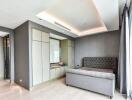 Modern bedroom with gray upholstered bed, built-in wardrobe, and recessed lighting