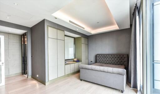 Modern bedroom with gray upholstered bed, built-in wardrobe, and recessed lighting