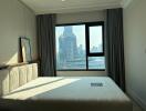 A bedroom with a large window offering city views