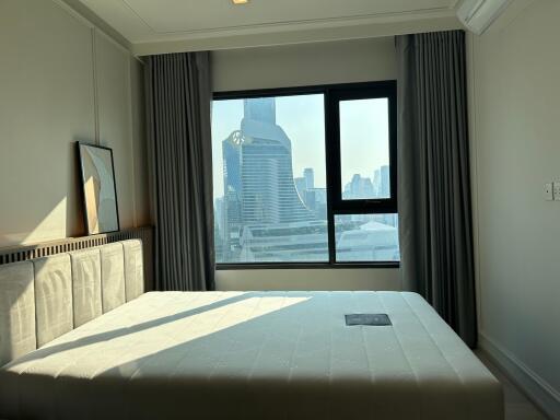 A bedroom with a large window offering city views