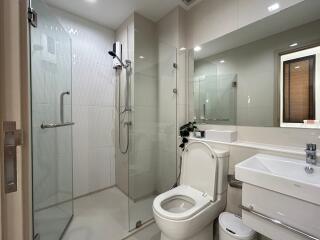 Modern bathroom with glass shower, toilet, and sink