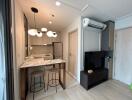 Modern kitchen and living area with marble countertop and TV