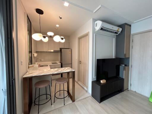 Modern kitchen and living area with marble countertop and TV