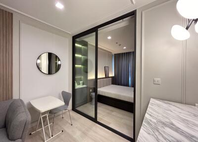 Modern bedroom with glass partition, seating and study area