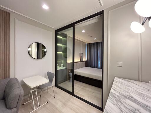 Modern bedroom with glass partition, seating and study area