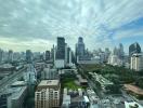 View of city skyline with tall buildings, greenery, and cloudy sky