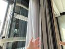 Close-up of a building window with curtains and a view of an air conditioning unit outside