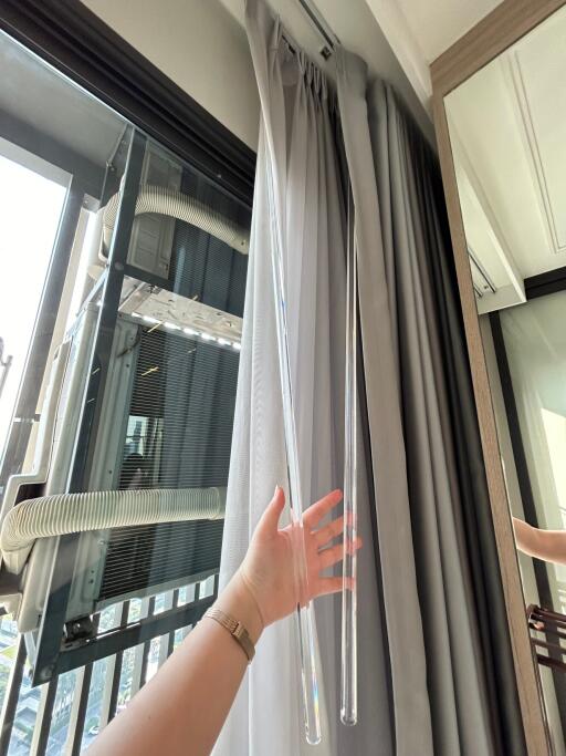 Close-up of a building window with curtains and a view of an air conditioning unit outside