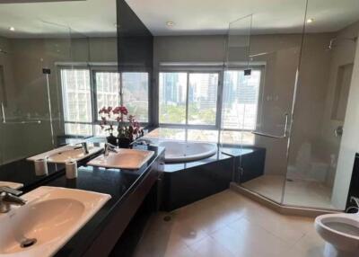 Modern bathroom with city view, featuring dual sinks, bathtub, and glass shower