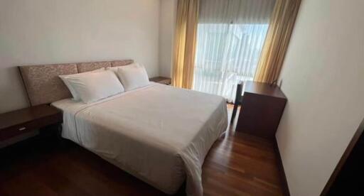 A cozy bedroom with a large bed and natural light from a window