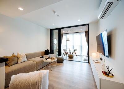 Modern living room with sofa, TV, and adjoining dining area
