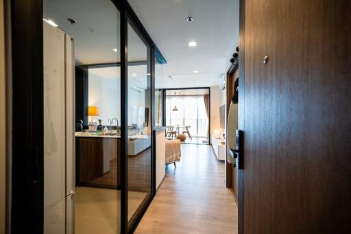 Modern apartment entryway leading to an open living space with kitchen.