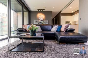 Modern living room with black leather sofa and glass coffee table