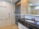 Modern bathroom with a shower area, black marble countertop, and large mirror