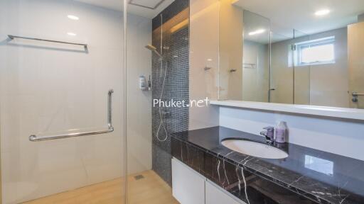 Modern bathroom with a shower area, black marble countertop, and large mirror