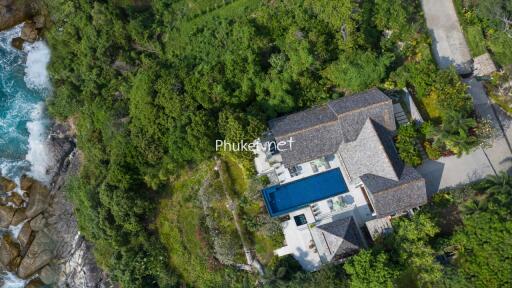 Aerial view of a house with a pool surrounded by lush greenery and located near the coast