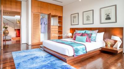 Spacious and modern bedroom with wooden flooring, stylish decor, and ample natural light.