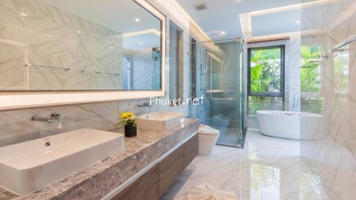 Modern bathroom with large vanity, shower, and bathtub with garden view