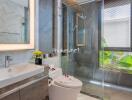 Modern bathroom with glass shower, vanity sink, and toilet